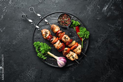 Chicken shish kebab with onions and tomatoes. Barbecue. On a black background. Top view. Free space for your text. Rustic style.
