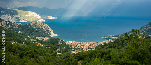 Aerial view from Turunc Bay, with sunbeam and cloudy sky. Marmaris, Turkey. Holiday and summer background. Curvy road and forest detail. Panoramic image.