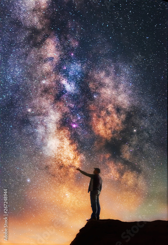 Man standing on the cliff and touching the milky way galaxy