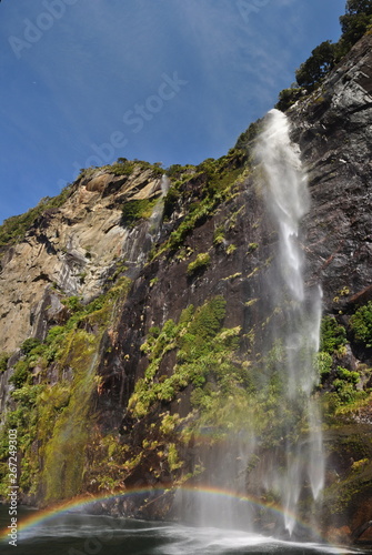 Waterfall in Milford Sound  New Zealand with a rainbow in the water spray 