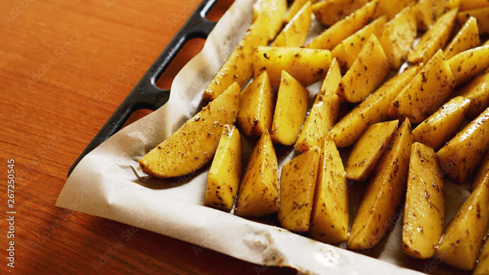 Sliced raw potatoes on a baking sheet with spices and rosemary, top view, copy space Sliced raw potatoes on a baking sheet with spices and rosemary, top view, copy space