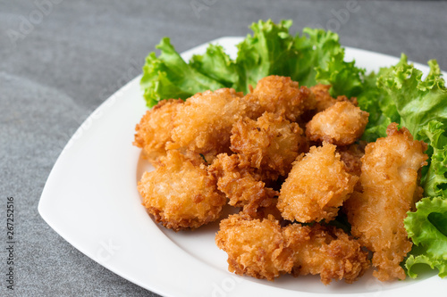 Fried chicken and lettuce in white dish on table.