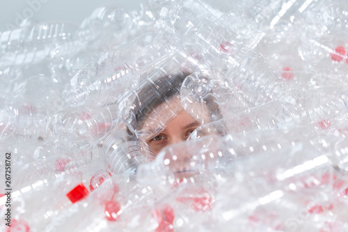 Plastic pollution problem and environment protection. Weak tired woman in a pile of plastic bottles. Save Earth concept. Clean our nature.