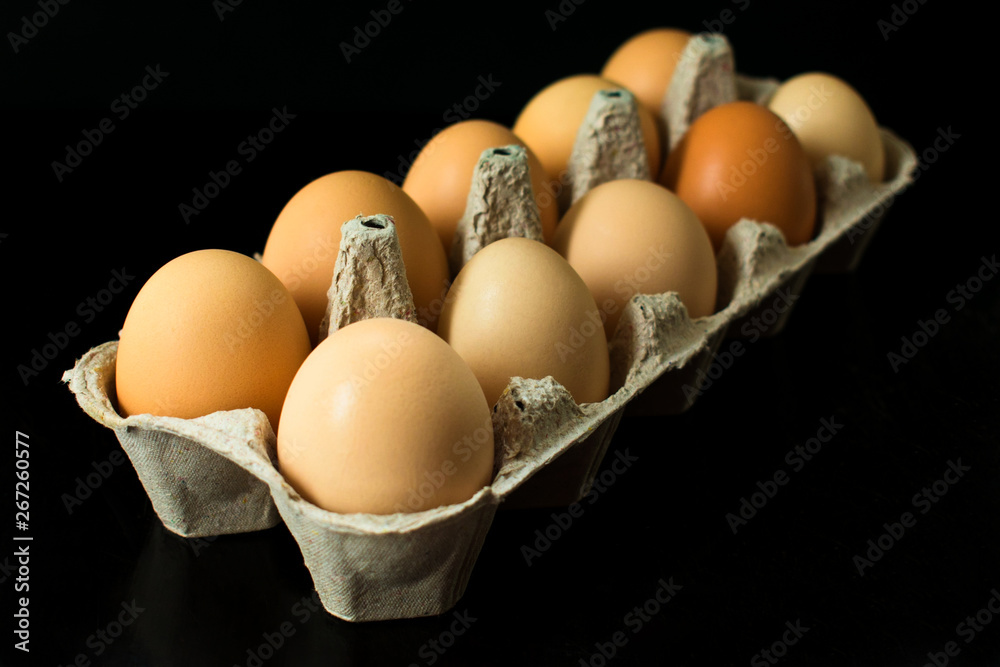 Chicken eggs in a cardboard container for the storage and transportation of chicken eggs isolated on black background Chicken eggs in a cardboard container for the storage and transportation of chicken eggs isolated on black background