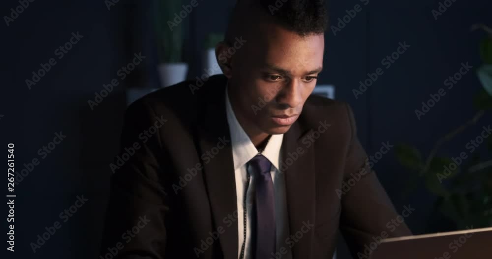 Businessman typing on laptop late in dark office Businessman typing on laptop late in dark office