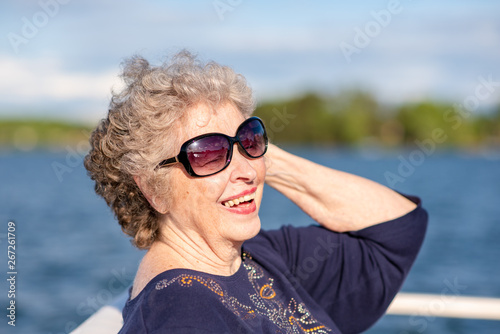 Beautiful,confident senior woman smiles and poses while boating on a beautiful lake on a sunny day.