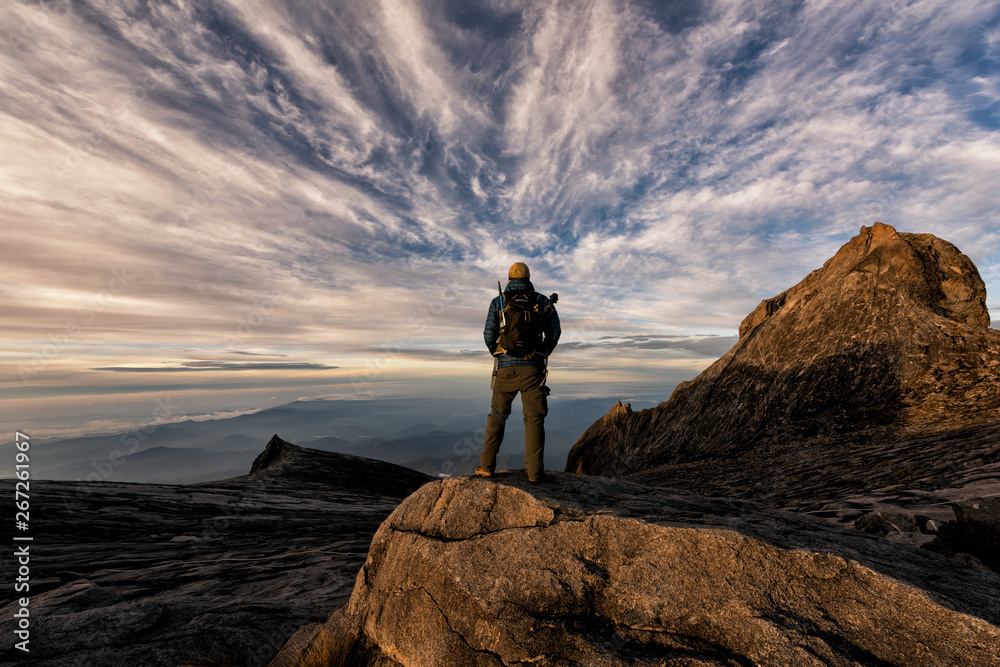 The climber stood back and watched the sun rise and breathed the fresh air in the morning at the top of Mount Kinabalu. Malaysia