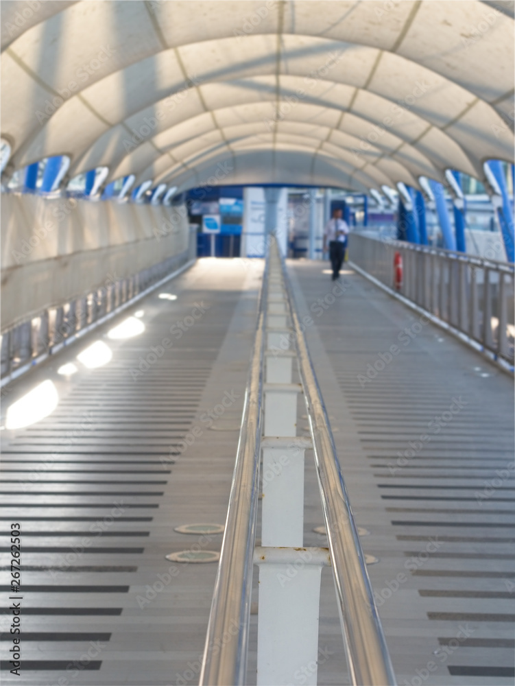 Obraz premium Perspective view of pathway with silver color handrails in the middle and white canvas roof