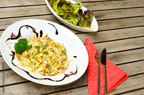 Kässpatzen mit Salat auf einem Holztisch photo