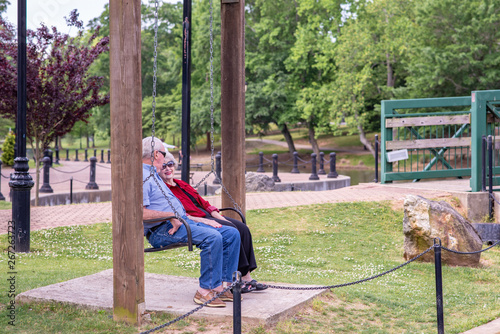 A beautiful senior couple enjoys the day at a park  sitting in a chair swing  on a spring day.