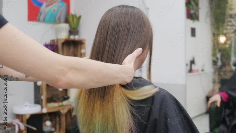 Professional woman hairdresser making creative hairstyle to girl in beauty salon.