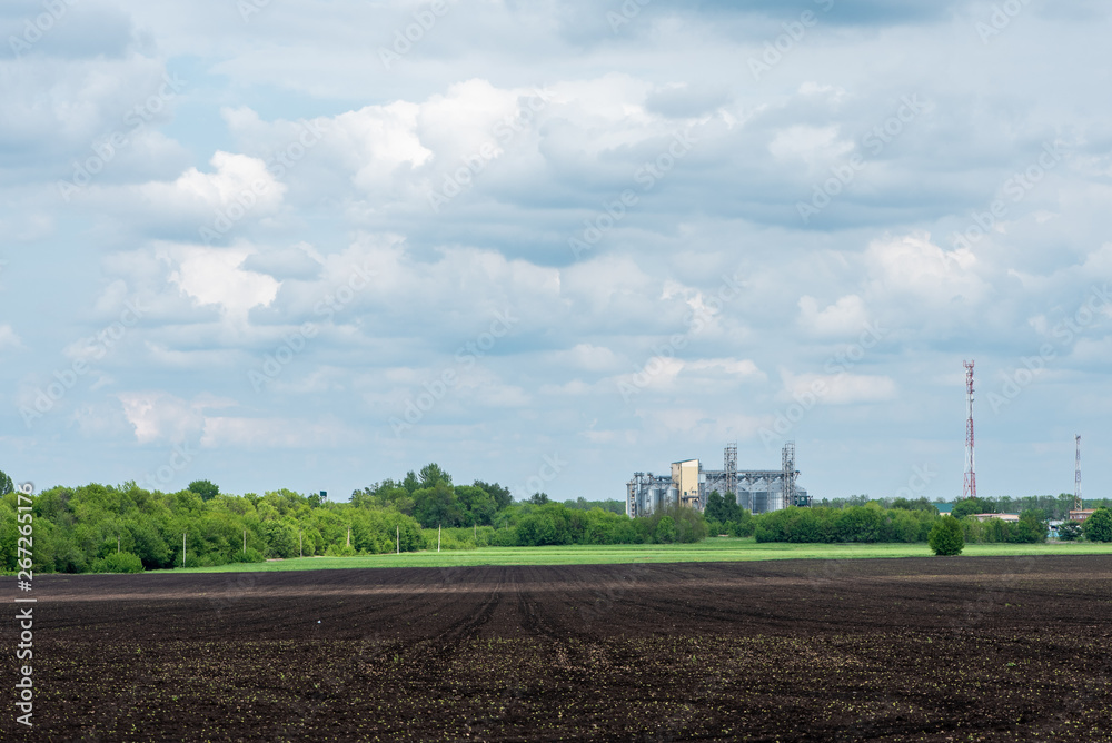 Plowed agricultural field and granary. Rural landscape.