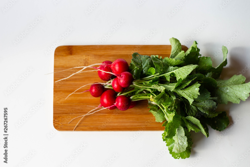 Fresh washed red round radishes on the wooden bamboo cutting board Fresh washed red round radishes on the wooden bamboo cutting board