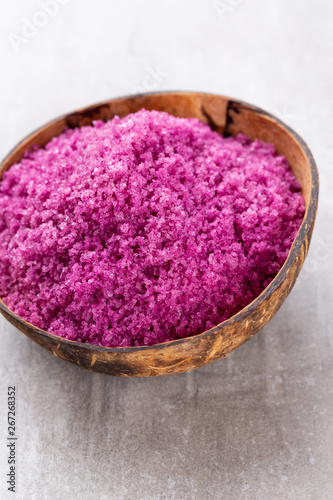 Sea salt in bowl, aroma oil in bottles, Wellness and flowers on grey textured background and flowers on vintage wooden background. Selective focus.