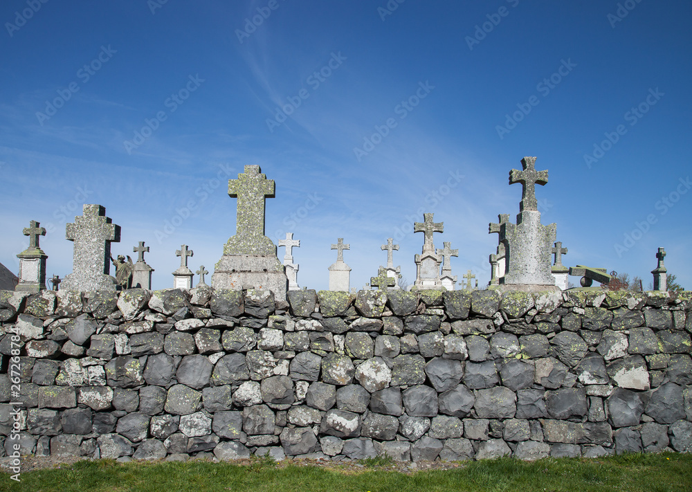 Croix du cimetière de Laguiole audessus d'un mur de roches basaltiques