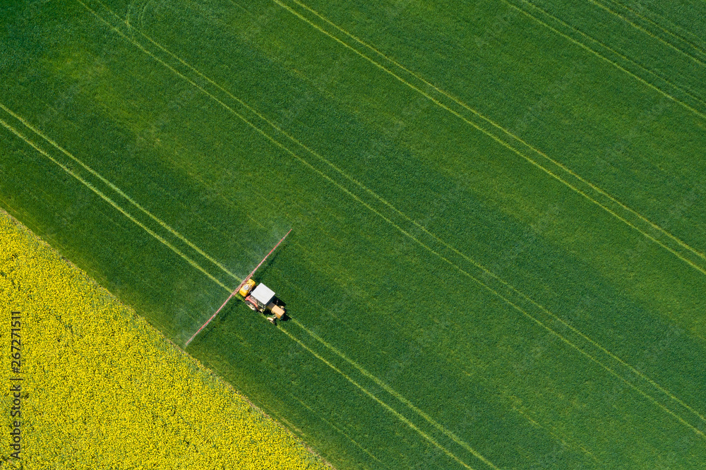 Obraz premium Aerial view of farming tractor plowing and spraying on field. Agriculture. View from above. Photo captured with drone.