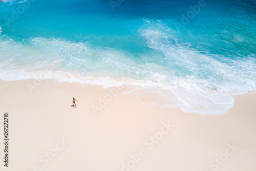 Top view from aerial. Bali drone shoot with ocean waves and white sand. People walk on beach