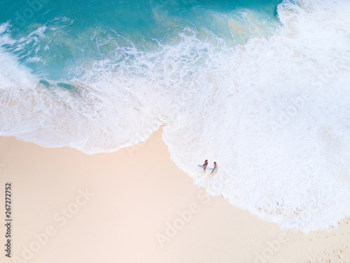 Top view from aerial. Bali drone shoot with ocean waves and white sand. People walk