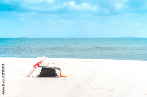 Fototapeta Naklejka Na Ścianę i Meble -  Graduation cap and certificated on the beach with beautiful sea in summer,Education in summer Concept