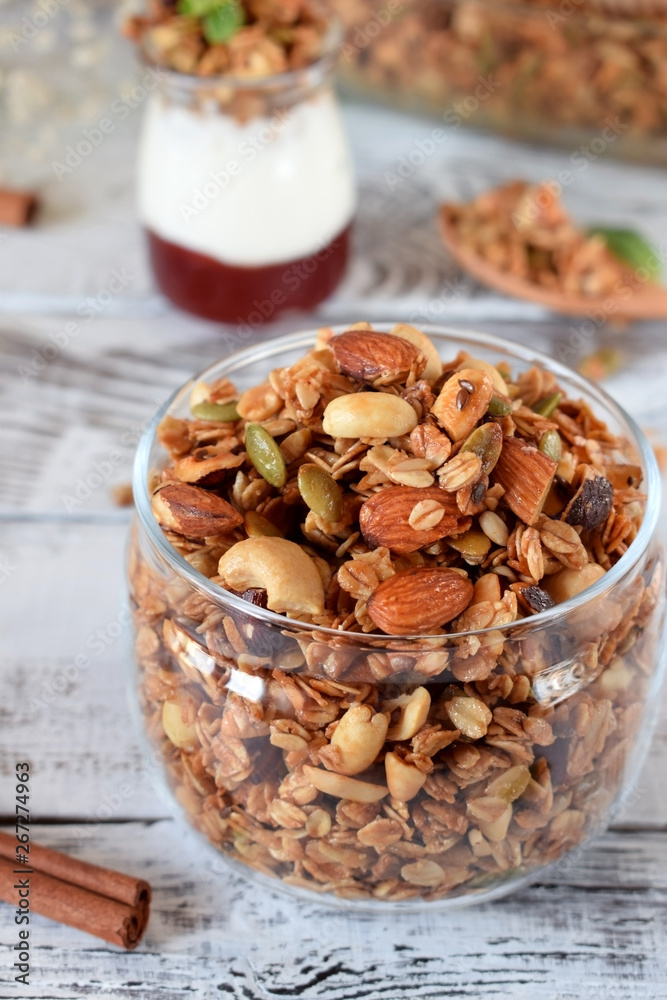 Obraz premium Granola with different nuts in a glass jar on the white wooden table