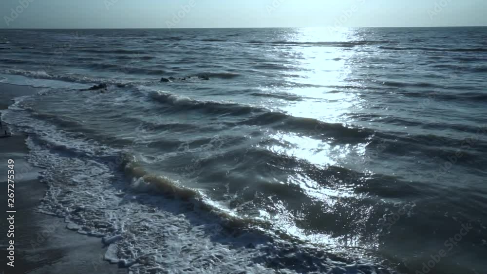 Blue, green, turquoise sea, wind, waves, sun, black stones, sunny path, summer, warm, windy, day, foam, surf, against the blue sky. Slow motion. Blue, green, turquoise sea, wind, waves, sun, black stones, sunny path, summer, warm, windy, day, foam, surf, against the blue sky. Slow motion.