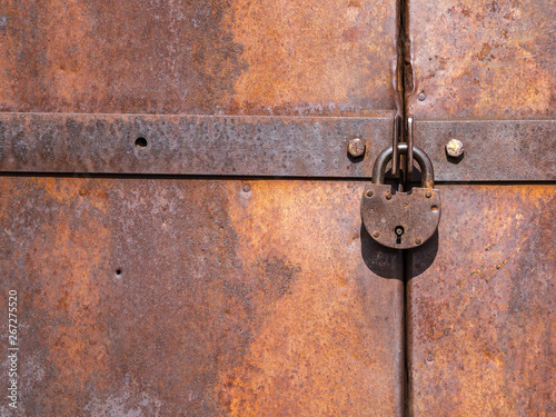 Foto Old lock hangs on metal doors covered in rust.