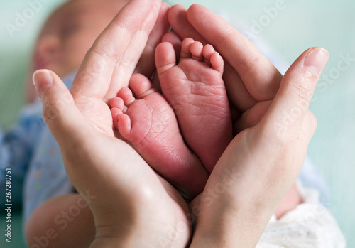 baby feet in mom's hands concept tenderness care (macro)