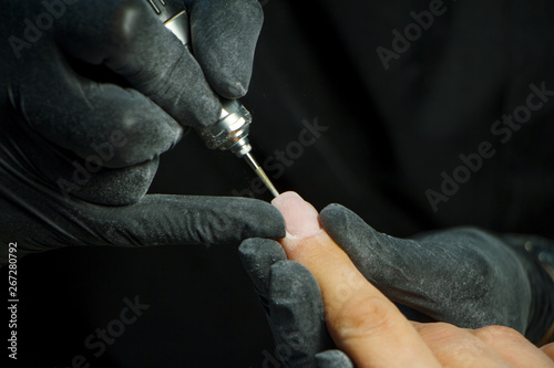 Manicure process close-up with nail polishing machine. Hardware manicure in modern beauty salon.