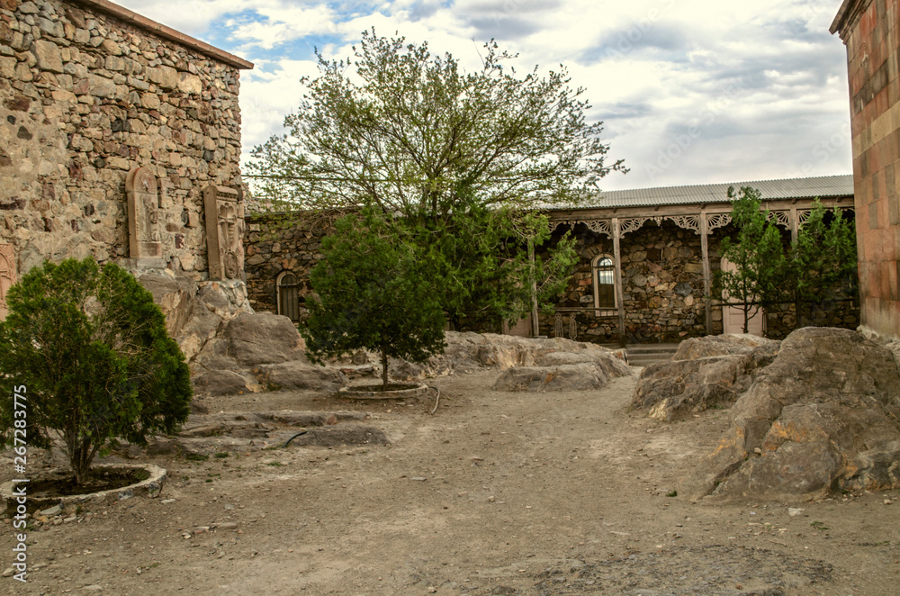 The courtyard of the medieval fortress of Khor Virap with living quarters, khachkars by the wall and trees growing among the stones