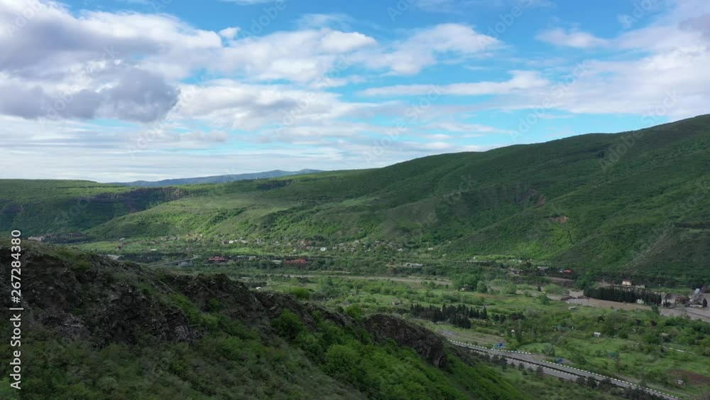 Freeway among the green mountains. Cloudy sky Aerial video
