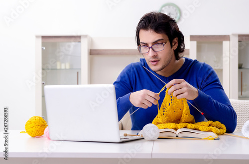 Young good looking man knitting at home photo