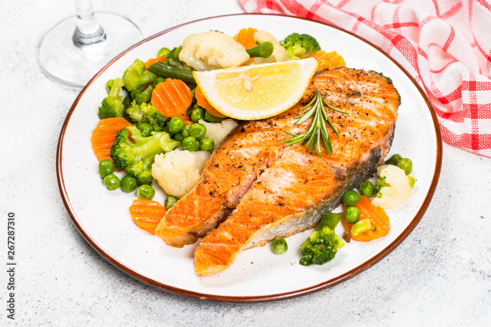 Grilled salmon steak with vegetables on white. Grilled salmon steak with vegetables on white.