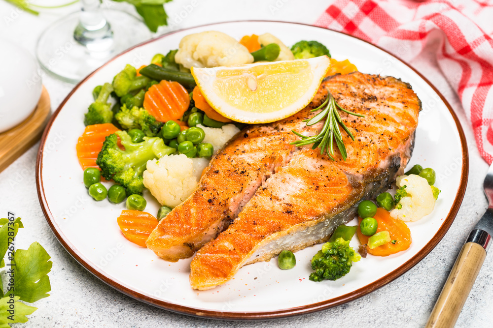 Grilled salmon steak with vegetables on white. Grilled salmon steak with vegetables on white.