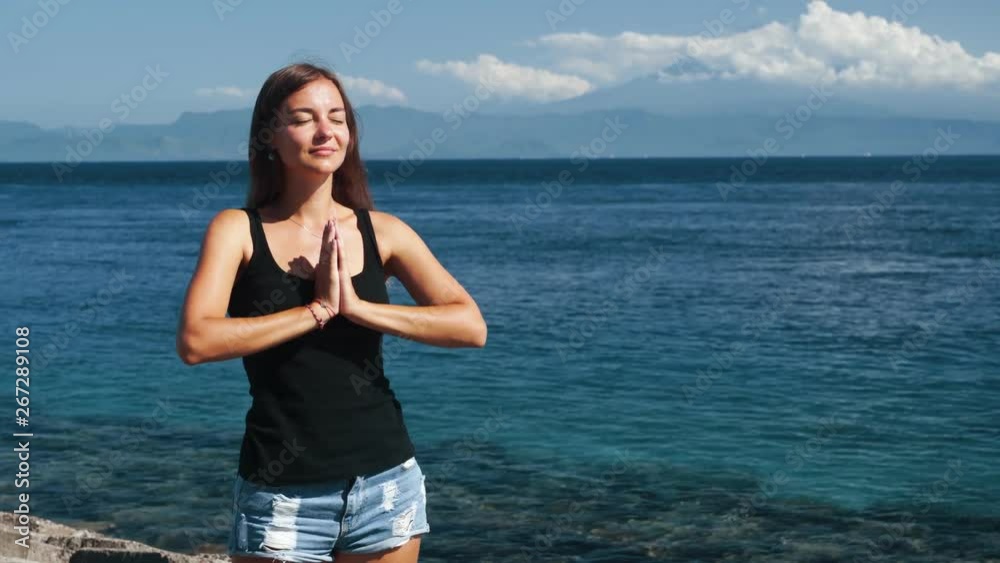 Portrait of young beautiful woman does yoga exercise, ocean on background Portrait of young beautiful woman does yoga exercise, ocean on background