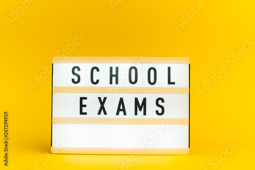 Photo of a light box with text, SCHOOL EXAMS, on isolated yellow background
