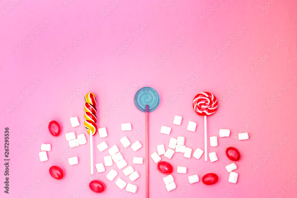 Flat lay composition with yummy lollipops and marshmallows and space for text on pink background