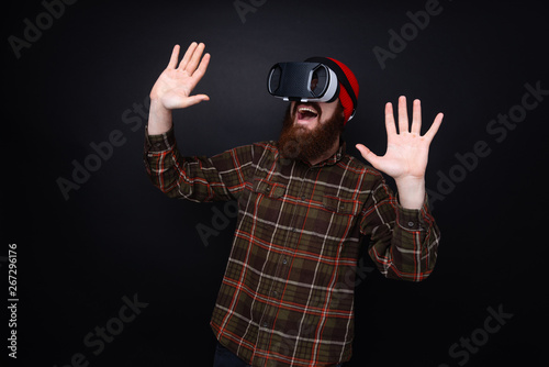 Photo of bearded man with Vr glasses, happy and scared by virtual reality