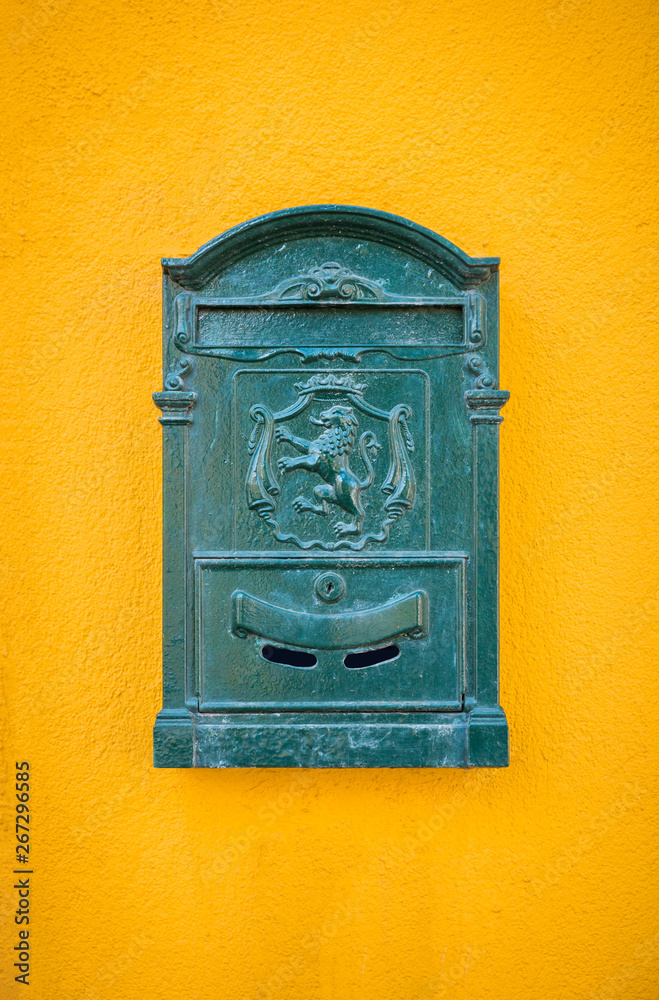 Green, old, vintage mailbox hanging on the yellow wall