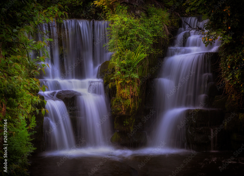 Obraz premium The waterfall at Penllergare Valley Woods on the Afon Llan river, easily accessible just off junction 47 of the M4 motorway in Swansea, UK.