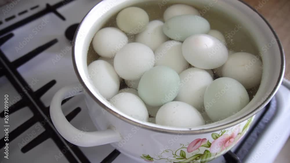 a group of white chicken eggs boiled in enamel pan on a gas stove in boiling water boils a group of white chicken eggs boiled in enamel pan on a gas stove in boiling water boils