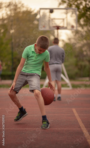 One boy, exercising dribbling ball between his legs.