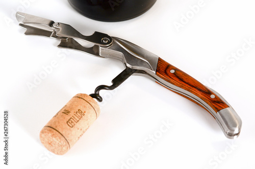 Open professional sommelier or waiter knife, bottle opener with corkscrew and with wine cork on it, close up macro.
