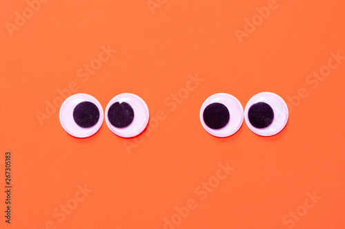 Googly eyes: One pair strabismus and squint mad googly eyes and one pair normal funny eyes next to each other on orange background. photo