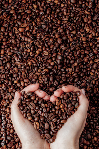 Coffee beans in man palms in form of a heart on coffee background