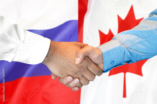 Business handshake on the background of two flags. Men handshake on the background of the Canada and Russia flag. Support concept