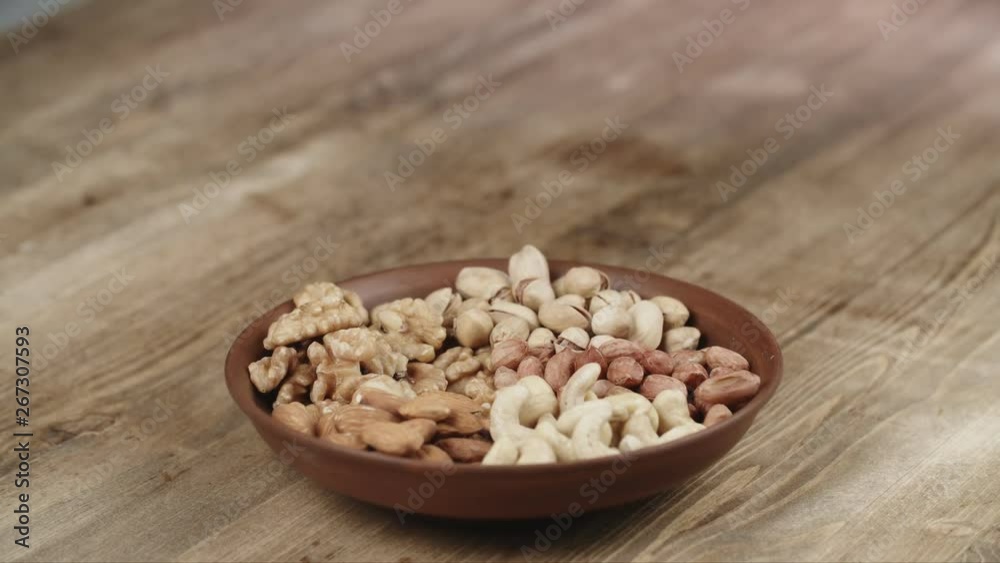 Woman Picks Up a single walnut, To Eat, From Her Bowl. took a nut on the left side Woman Picks Up a single walnut, To Eat, From Her Bowl. took a nut on the left side