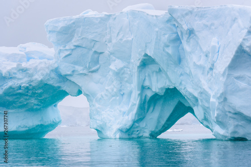 Beautiful turquoise blue iceberg floating in the Antarctic, against a foggy background