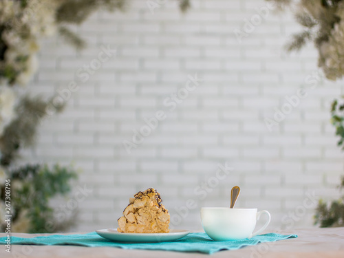 a piece of cake and a Cup of tea, a white brick wall and plants
