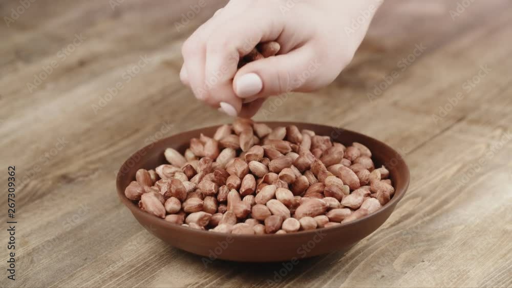 Woman Picks Up a handful of peanuts, To Eat, From Her Bowl. took a nut on the left side Woman Picks Up a handful of peanuts, To Eat, From Her Bowl. took a nut on the left side