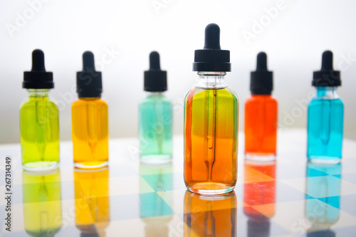 Vape concept. Beautiful colorful vape liquid glass bottles outdoor on stones. Useful as background or electronic cigarette advertisement.